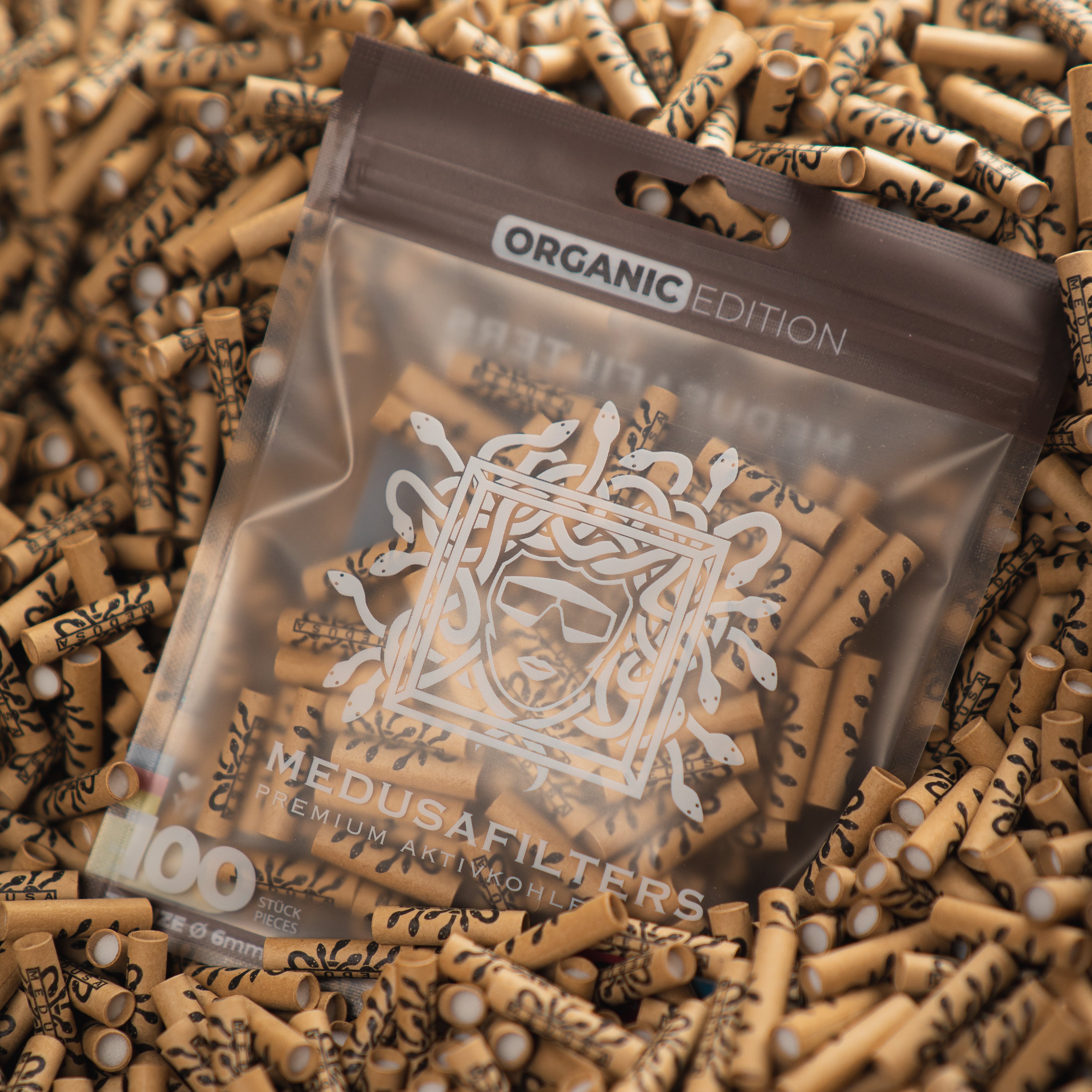 Medusafilters Premium Aktivkohlefilter mit Kokosnuss-Aktivkohle und veganen Fasercaps 100er Packung ORGANIC Edition Tip Size 6 mm in Filter liegend