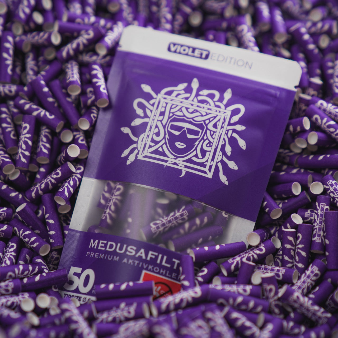 Medusafilters Premium Aktivkohlefilter mit Kokosnuss-Aktivkohle und veganen Fasercaps 50er Packung VIOLET Edition Tip Size 6 mm in Filter liegend 
